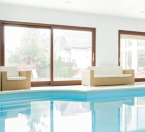 bösch optima pool Deckenlüftung weißes Hallenbad mit braunen Sofas und große Fenster mit Holzrahmen | © photographee.eu - Fotolia