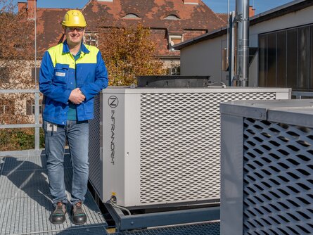 Mitarbeiter von voestalpine BÖHLER Aerospace vor installierter INFRANORM®-Kühleinheit des Sustainable Hall Conditioning Systems – energieeffiziente Klimatisierung am Standort Kapfenberg