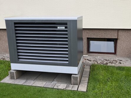 Außeneinheit einer bösch Luft-Wärmepumpe vom Typ MOZART R32, installiert neben einem Einfamilienhaus auf einem gepflasterten Fundament. | © Walter Bösch GmbH & Co KG