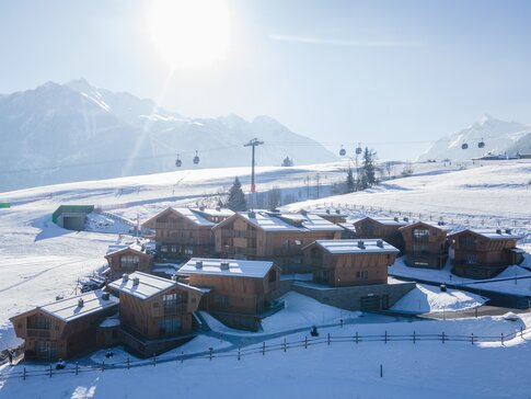 Hotel-Dorf Zaglgut im Winter mit direkter Lage an der Skipiste und Blick auf die verschneiten Alpen – ausgestattet mit Pelletheizung, Lüftungsanlage und Gebäudeautomation von bösch. | © Hotel & Chalets Zaglgut