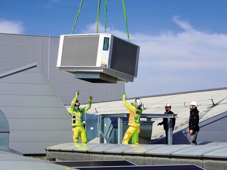 Helikopter transportiert Komponenten des Sustainable Hall Conditioning Systems auf das Hallendach des ENGEL-Werks in Schwertberg