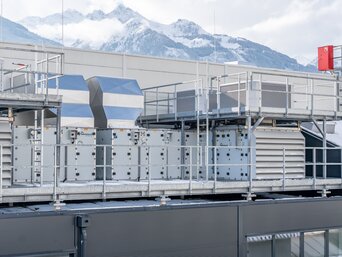 Gesamtansicht der Lüftungs- und Kühleinheiten des Sustainable Hall Conditioning Systems auf dem Dach des Senoplast-Werks in Piesendorf vor Alpenkulisse