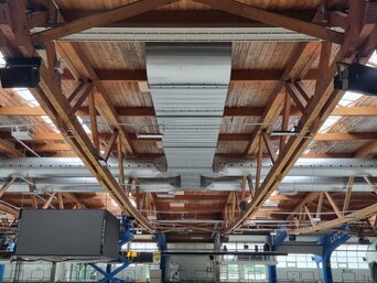 Hauptluftkanal unter den Holzbinderträgern; Anbindung der Hallenluftführung an das RLT-Gerät. | © Frey & Partner GmbH